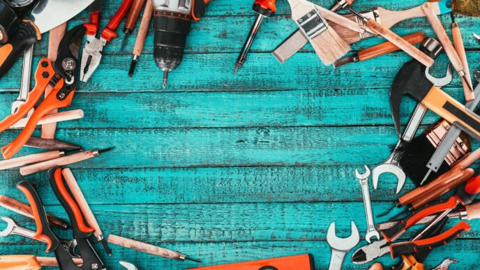 Assorted home repair tools on a rustic workbench with sunlight highlighting their textures.