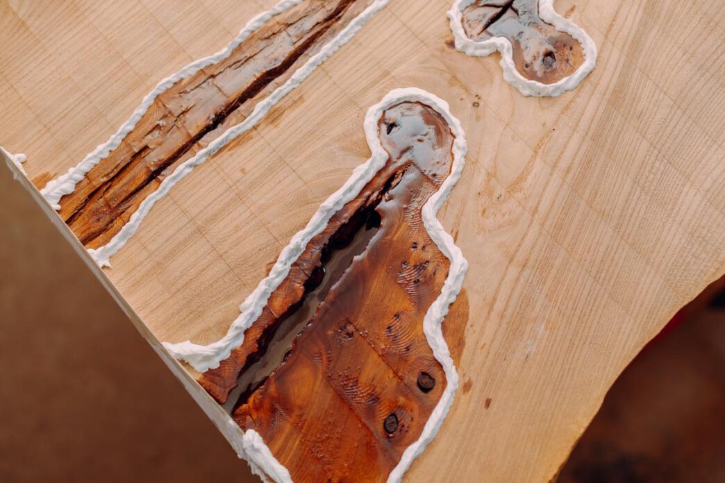 Close-up of a worn wooden table with mold, set in a sunlit living room.